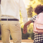 African American father and daughter running trough park. Close up.