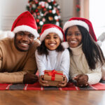 Portrait of happy mom, dad and child in santa hats celebrating xmas