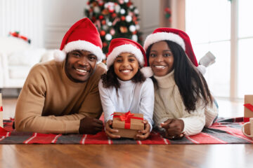 Portrait of happy mom, dad and child in santa hats celebrating xmas
