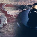 Photo of a gavel and handcuffs on a wooden surface.